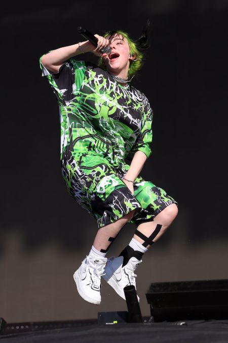 billie jumping on stage wearing a green and black outfit 